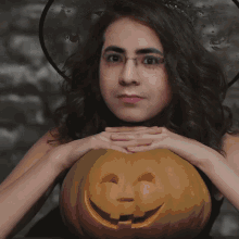 a woman in a witch hat is holding a carved pumpkin with the words wish acufur hall written on it