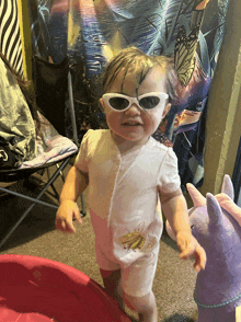 a little girl wearing white sunglasses and a white shirt with a banana on it