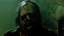 a close up of a zombie 's face with blood on it in a dark room .