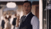 a man in a suit holds an ice cream cone in his hand