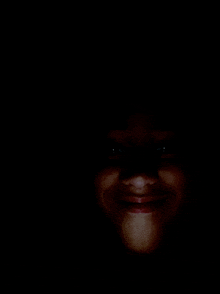 a close up of a person 's face in the dark smiling .