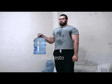 a man with a beard is holding a large bottle of water in his hand .