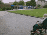 an elderly woman sits in a wheelchair on a sidewalk in front of a building that says ' a ' on it