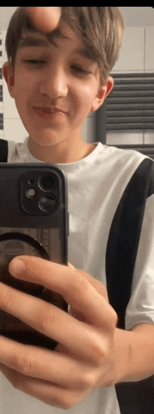 a young boy is taking a picture of himself in the mirror with his phone .