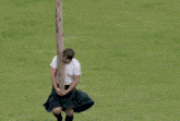 a man in a kilt is standing on top of a large piece of wood with the words caber toss below him