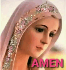 a statue of the virgin mary wearing a pink veil with flowers on it and the words amen written on it .