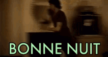 a blurry picture of a person standing in front of a counter with the words `` bonne nuit '' written in green .