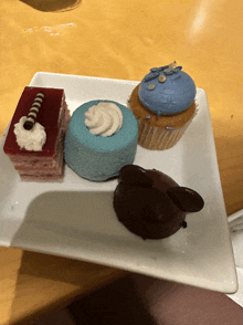 a plate of desserts including a blue cupcake and a red cake