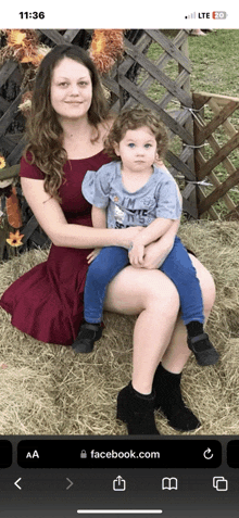 a woman in a red dress is holding a baby in her lap