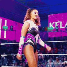 a woman in a leotard is standing in a wrestling ring in front of a crowd