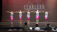 a group of dancers are performing in front of a fearless sign