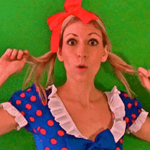 a woman in a blue dress with red polka dots and a red bow in her hair