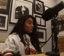 a woman sitting in front of a microphone with a cup of coffee