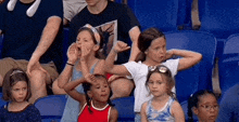 a group of young girls are sitting in a stadium watching a sports game .