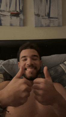 a shirtless man is giving a thumbs up in front of a sailboat painting