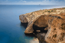 a cliff overlooking a body of water with a small island in the background