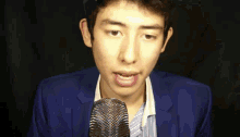 a young man in a blue suit is speaking into a microphone