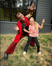 a girl in a pink shirt stands next to a man in a red and black suit