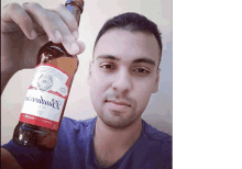 a man is holding a bottle of budweiser in his hand