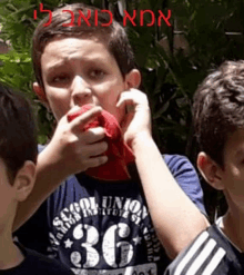 a boy wearing a shirt with the number 36 on it eating a red apple