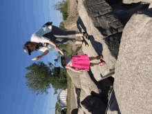 a man and a little girl are standing on a rocky hillside