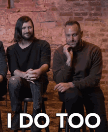 a group of men sit on stools in front of a brick wall with the words " i do too " in white