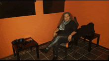 a woman sits in a chair with her legs crossed in a dark room