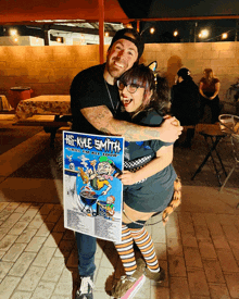 a man holding a kyle smith poster hugs a woman