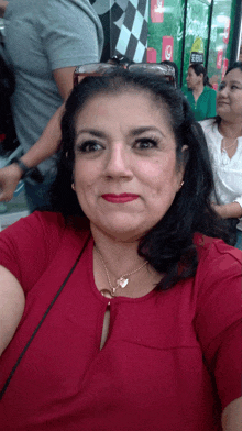 a woman in a red shirt takes a selfie in front of a sign that says ' coca cola ' on it