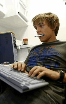 a young man is sitting at a desk using a dell computer .