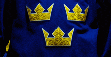 three gold crowns are embroidered on a blue background