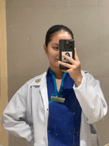 a woman in a lab coat takes a picture of herself in a mirror