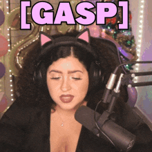 a woman wearing cat ears behind a microphone with the word gasp written above her