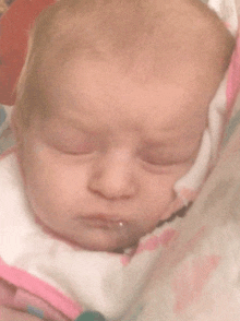 a close up of a baby 's face with a pink and white bib on