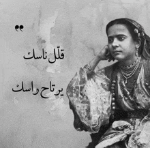 a black and white photo of a woman with arabic writing on the wall behind her