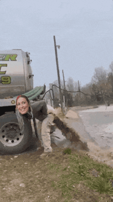 a woman is sticking her head out of a hole in the ground next to a truck that says power 9