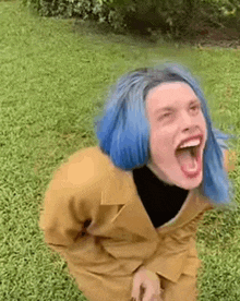 a woman with blue hair is laughing with her mouth open .