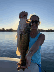 a woman is holding a large bass in her hands