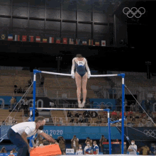 a woman in a blue leotard with the number 396 on it is doing a routine on a parallel bars