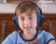 a young boy wearing headphones and a blue shirt is making a funny face .