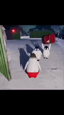 three penguins are walking in the snow and one is carrying a red bag