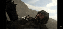 a man in a helmet is laying on the ground in front of mountains