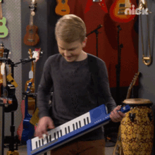 a boy is playing a keyboard in front of a wall with guitars on it and the word nick on it