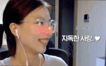 a woman wearing glasses and ear buds is smiling with a heart in the corner