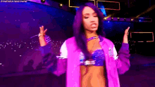 a woman with purple hair and a purple jacket is standing in front of a crowd .