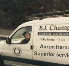 a man is driving a white van that says b.j. champ on the side