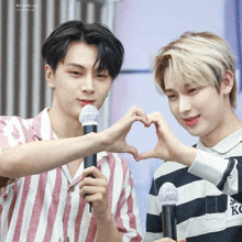 two young men are making a heart shape with their hands in front of microphones