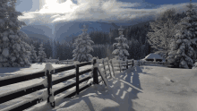 a snowy landscape with a fence in the foreground and mountains in the background