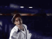 a man is singing into a microphone while wearing a white shirt and suspenders .