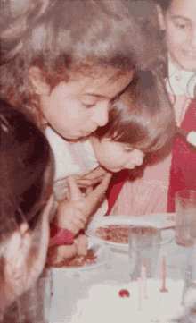 a group of children are sitting at a table eating food